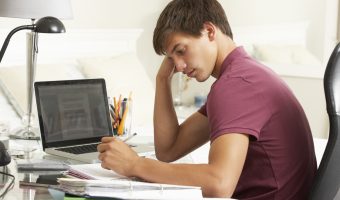Teenage Boy Studying At Desk In Bedroom